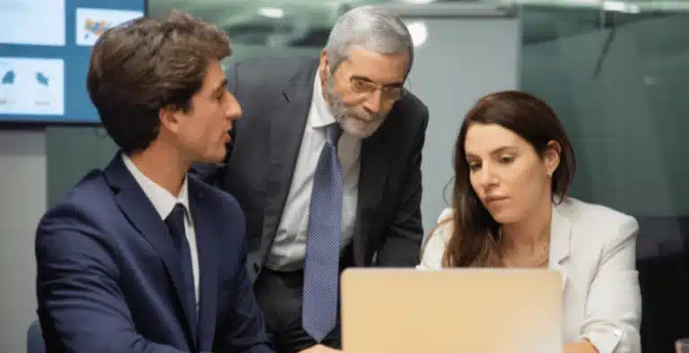 Três pessoas em frente ao computador em uma empresa