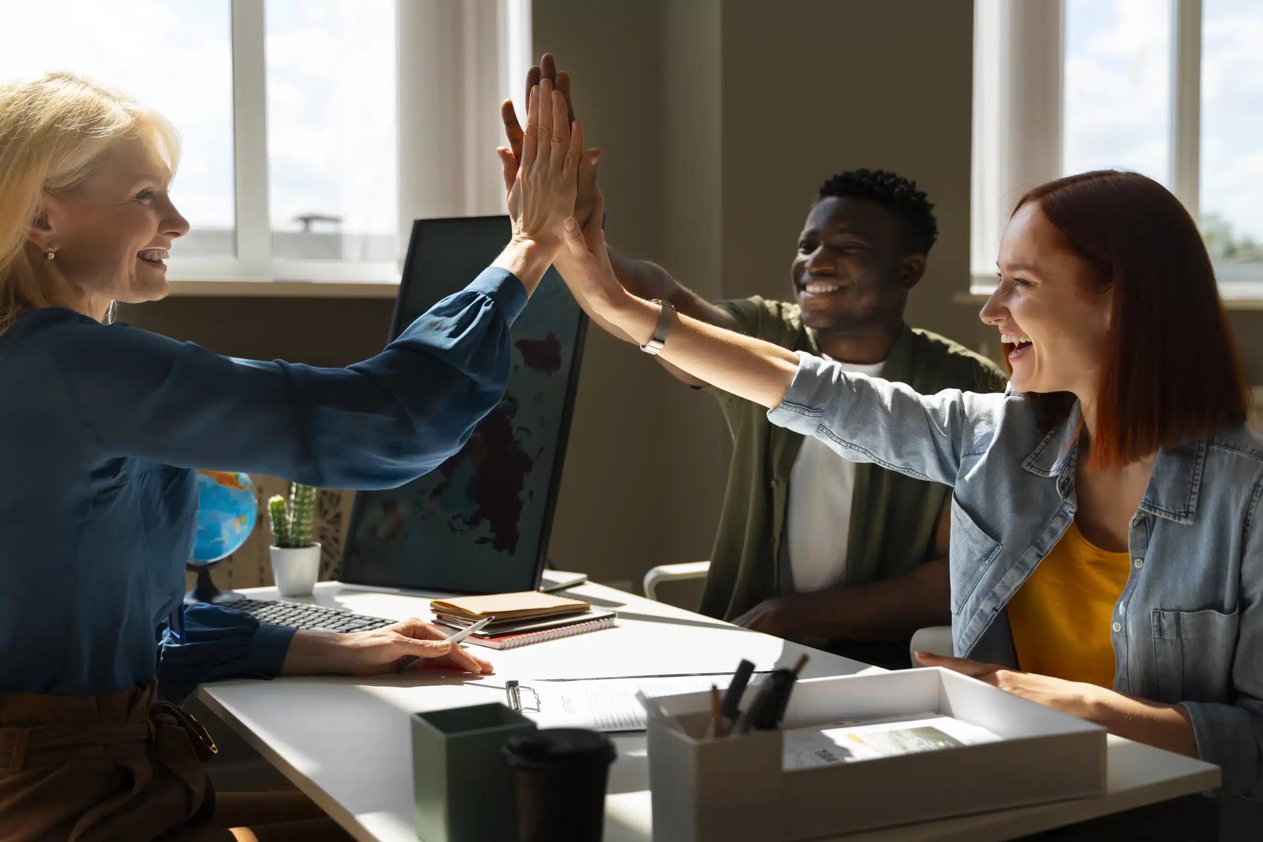 Três colaboradores comemorando batendo as mãos