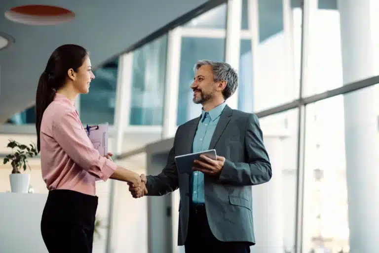Homem e mulher apertando as mãos no meio corporativo