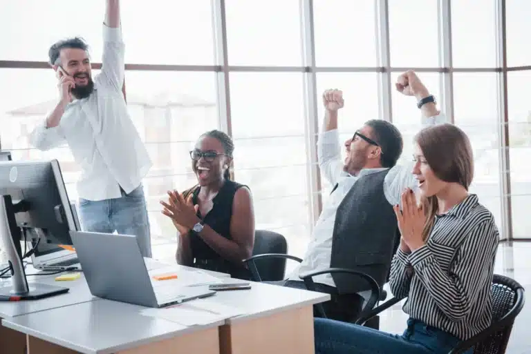 colaboradores comemorando em frente ao computador