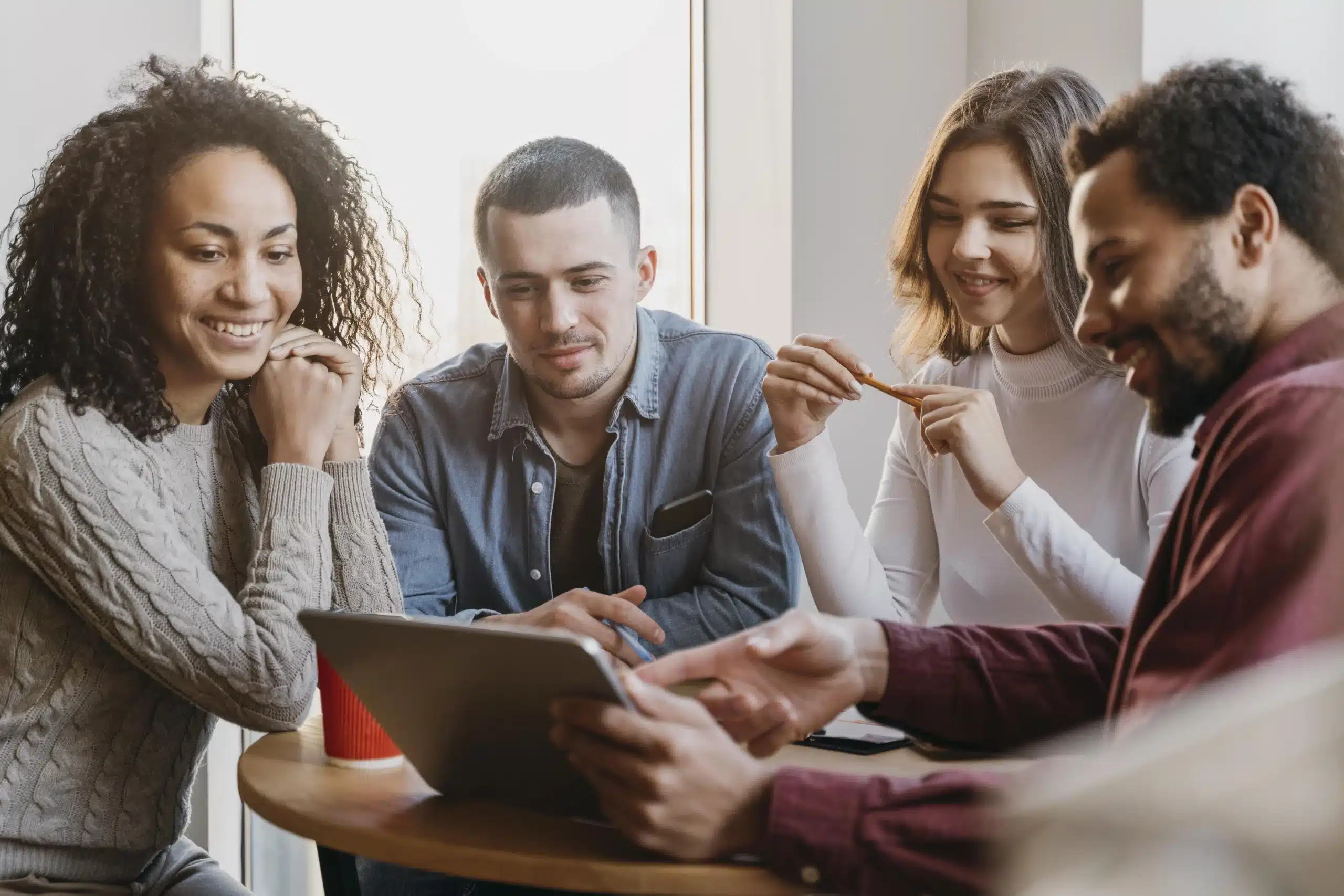 Quatro pessoas em frente a um tablet sorrindo
