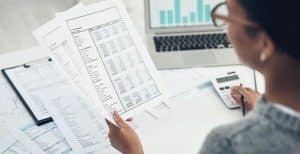 Mulher na mesa olhando um papel com o plano de cargos e salários de uma empresa