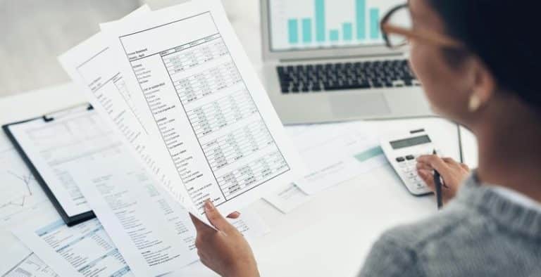 Mulher na mesa olhando um papel com o plano de cargos e salários de uma empresa