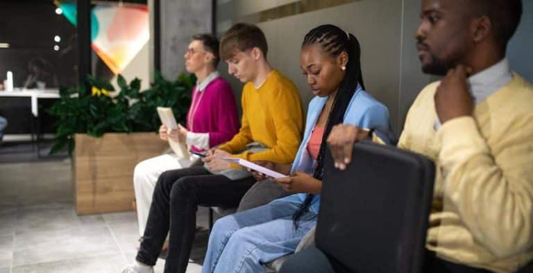 Pessoas sentadas esperando para fazer o teste situacional em uma entrevista de emprego